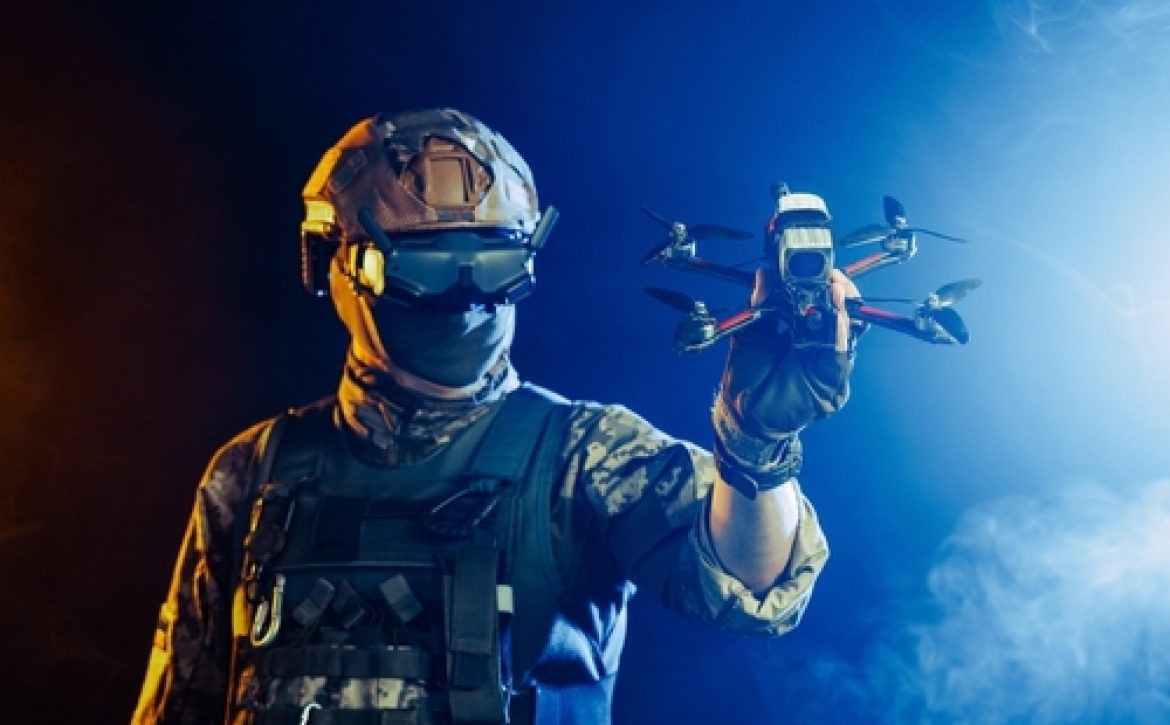 Soldier,In,Gear,Holds,Drone,Against,A,Red,And,Blue