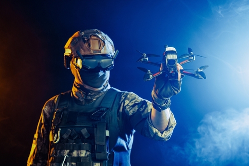 Soldier,In,Gear,Holds,Drone,Against,A,Red,And,Blue
